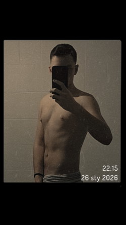 Shirtless man with short dark hair taking mirror selfie, holding phone to cover face, wearing striped underwear against