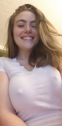 Smiling woman with long blonde hair wearing a white t-shirt, lying down indoors.