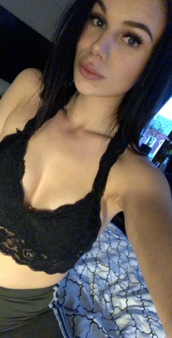 Woman with long dark hair in a black bra and patterned shirt.