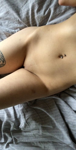 Person with a tattoo on their arm lying on a bed with a patterned blanket.