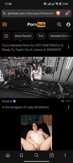 Curvy woman in white lingerie and hat poses in a dungeon-like room with BDSM equipment.