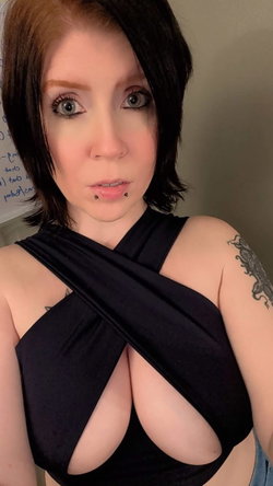 Woman with short dark hair and piercings in a black top.