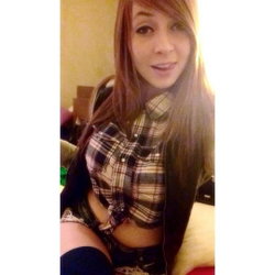 A woman with long red hair and a plaid shirt sits on a couch.