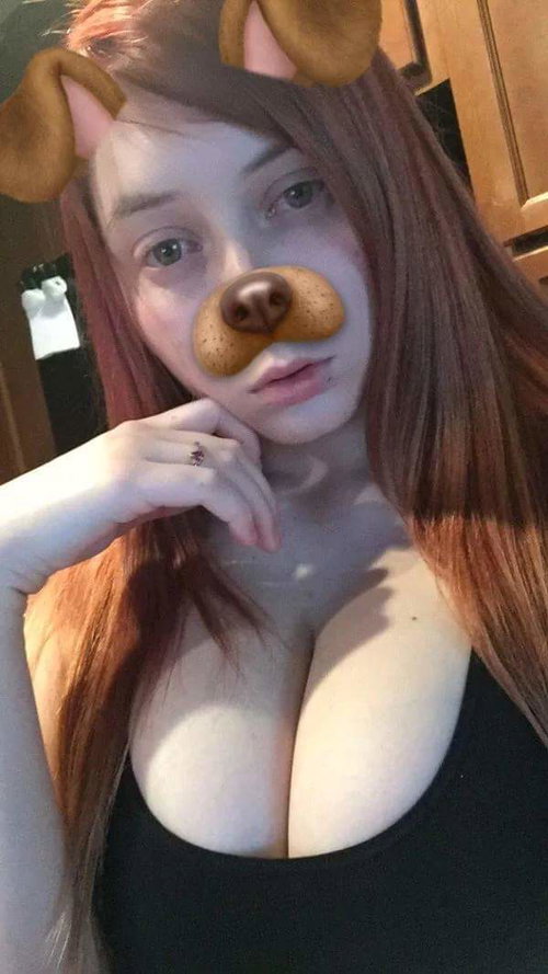 Woman with long brown hair wearing a dog filter, posing in a black top indoors.