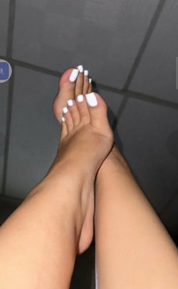 Person with painted toenails standing on a tiled floor.