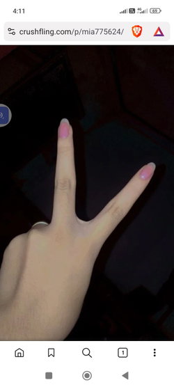 A hand with pink nail polish making a peace sign in a dimly lit room.