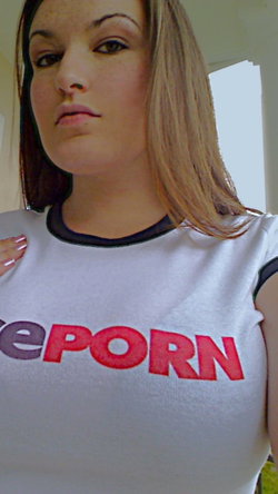Blonde woman in a white t-shirt with red text, looking serious.