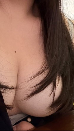 Curvy brunette with long dark hair shows cleavage in a close-up indoor view.