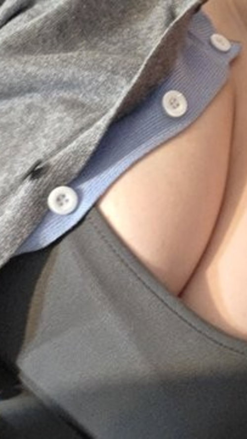 Close-up of a person's chest with a gray top partially unbuttoned, revealing skin and a blue undershirt.