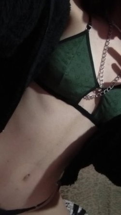 Close-up of a person wearing a green lace bra under a black fuzzy hoodie, with a silver chain necklace visible.