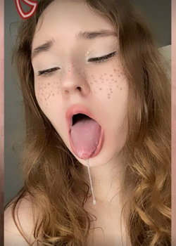 A young woman with freckles and long hair sticks out her tongue.