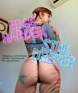 A woman with short red hair and extensive tattoos poses from behind in a striped top and thong, showcasing her curvy
