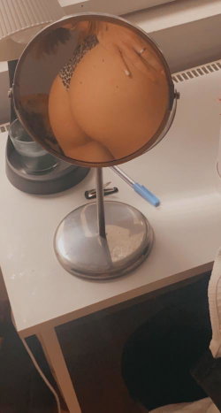 Reflection in a round mirror shows a person's bare back and buttocks, wearing leopard-print underwear, with a hand