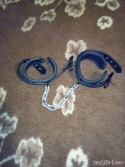Black plastic handcuffs with a metal chain lie on a brown patterned carpet.