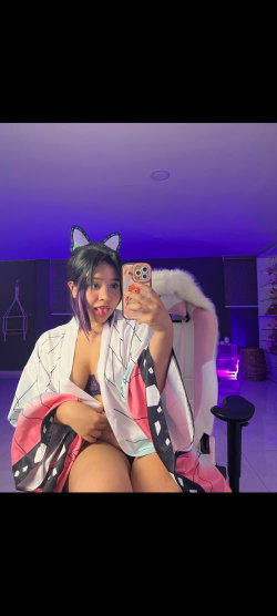 A person with dark hair and cat ears takes a selfie in a cosplay outfit.