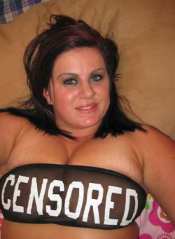 Curvy woman with dark hair lying on a couch, wearing a sheer top with 'CENSORED' printed across the chest.