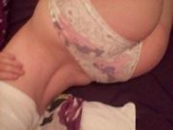 Close-up of a person's lower back and hips wearing floral lace underwear, hand resting on the side, lying on dark