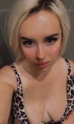 Blonde woman in a leopard print top looking directly at the camera.