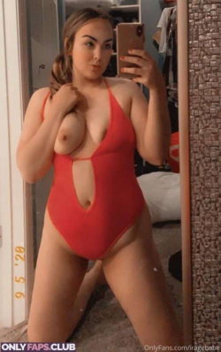 Woman in red cutout one-piece swimsuit takes mirror selfie, hand on chest, bare breasts visible, standing in bedroom.