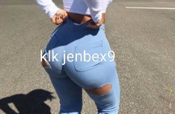 Curvy woman in ripped blue jeans and white top, standing outdoors on pavement, hands on hips.