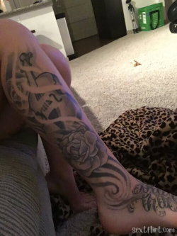 Person with detailed leg tattoos, wearing striped pants, sitting on carpeted floor near leopard-print fabric.