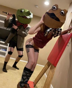 Two people in animal masks and playful outfits, one leaning on a red chair, wearing fishnet stockings and patterned