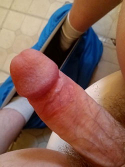 Close-up of a penis with visible pubic hair, partially covered by blue fabric, on a tiled floor.