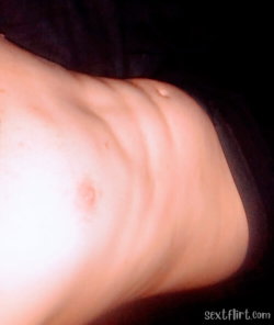 Close-up of a person's lower abdomen and hip area, partially covered by dark fabric, with visible skin texture and