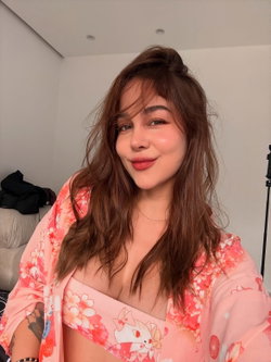 A woman with long brown hair and a floral robe smiles at the camera.