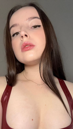 Brunette woman with long hair, glossy lips in red top, close-up indoor selfie.