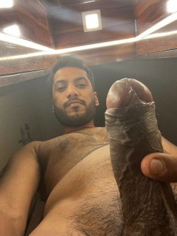 Shirtless man with dark hair and facial hair takes a selfie in a wooden sauna.