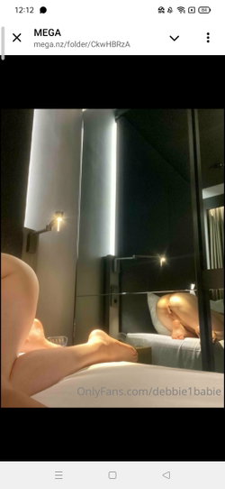 A person with a curvy build lies on a bed in a dimly lit room, feet and lower body visible, reflected in a mirror.