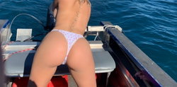 Blonde woman in white bikini with heart pattern on a boat.