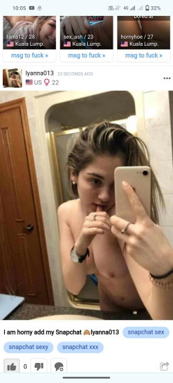 A young woman takes a mirror selfie in a bathroom, topless with one hand near her mouth and the other holding a phone,