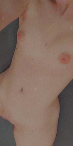 Close-up of a bare chest with visible nipples and navel, skin showing minor blemishes, lying on a dark surface.