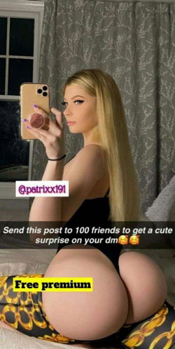 Blonde woman with long hair takes a mirror selfie in black top and patterned bottoms, showing her backside in a bedroom
