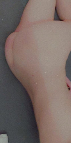 Close-up of a person's bare foot and lower leg resting on a dark surface, skin smooth with slight natural texture.