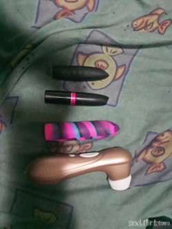 Four vibrators of varying designs and colors arranged on a green blanket with cartoon fish patterns.