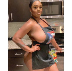 Curvy Black woman in a Puerto Rican flag halter top and short skirt, posing in a kitchen with one hand on hip.