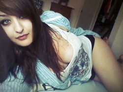 Brunette woman with long hair lying on bed, wearing a white tank top and black underwear, partially covered by a