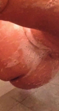 Close-up of a foot with visible skin texture and pores, resting on a tiled surface.