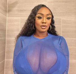 A woman with curly dark hair and hoop earrings wears a sheer blue top, standing in a tiled bathroom.