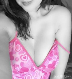 A woman with dark hair wearing a pink patterned top with thin straps, shown from the chest up in a close-up