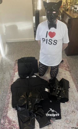 Person in black pig mask and bow tie, wearing white 'I ❤️ PISS' t-shirt and patterned leggings, kneeling beside