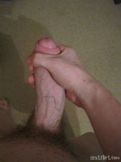 Close-up of a hand holding a hairy foot, showing visible veins and skin texture on a carpeted floor.