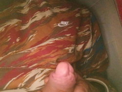 A person in camouflage Nike shorts with a finger pointing at the logo.