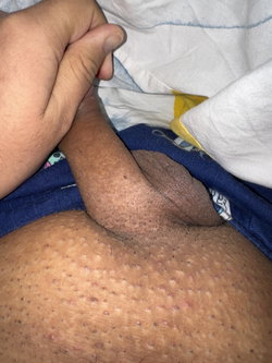 Person lying on a bed with a hand resting on their thigh.