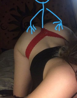 Curvy woman in red lace bra and black bottoms lying on bed with patterned blanket, back to camera.