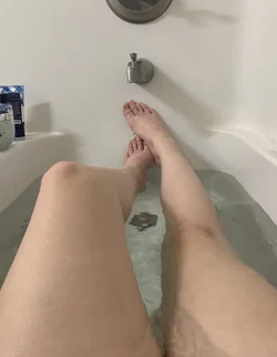 Person with light skin tone relaxing in a bathtub with bubbles.