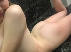 Close-up of a person's bare legs and lower body lying on a dark tiled surface, partially obscured by angle.